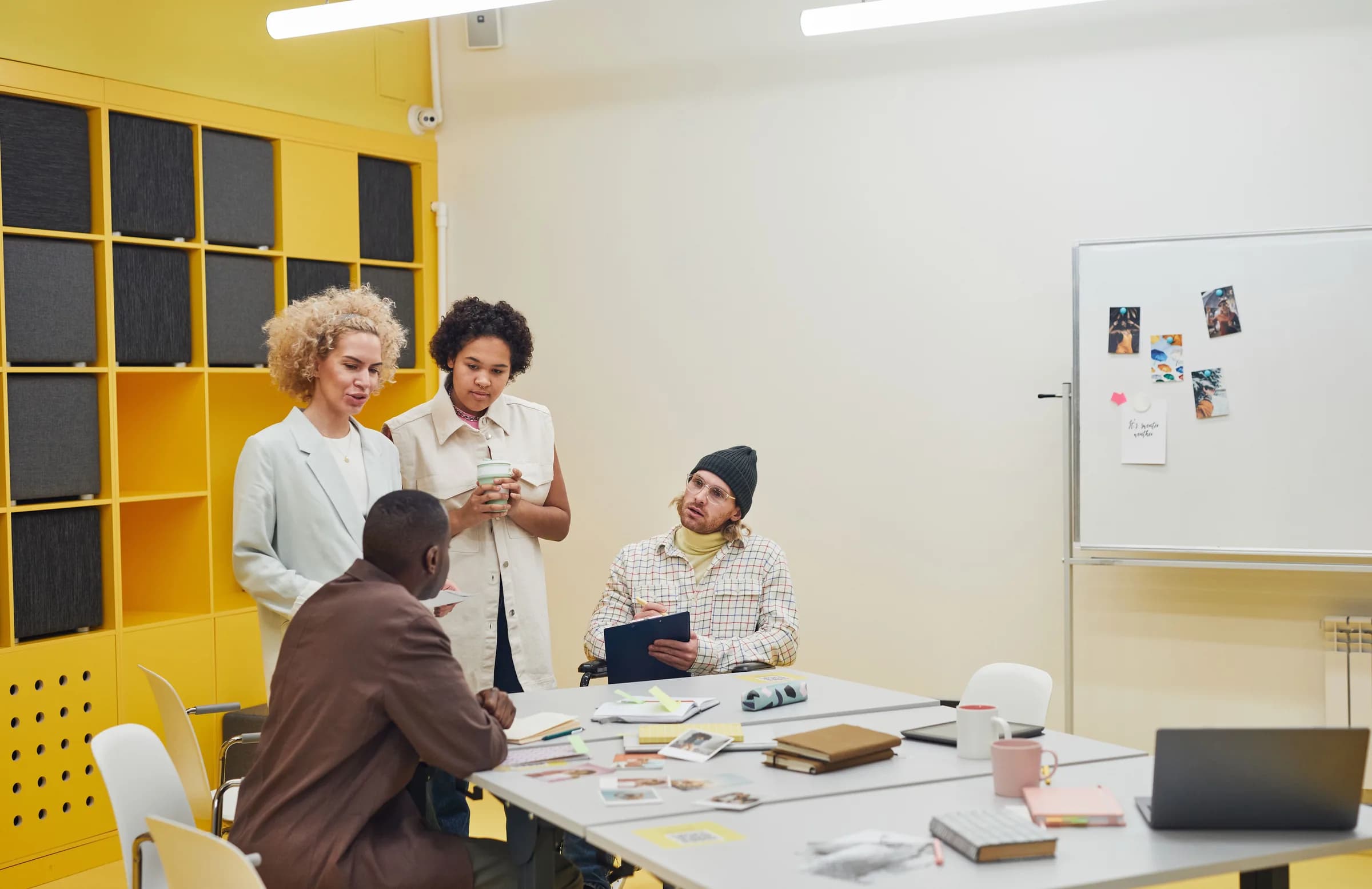 An agency team talks around a table in a bright, colourful meeting room.